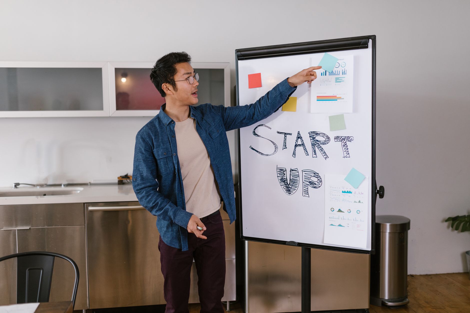 Un homme présente un plan de start-up sur un tableau blanc dans un environnement de bureau moderne.